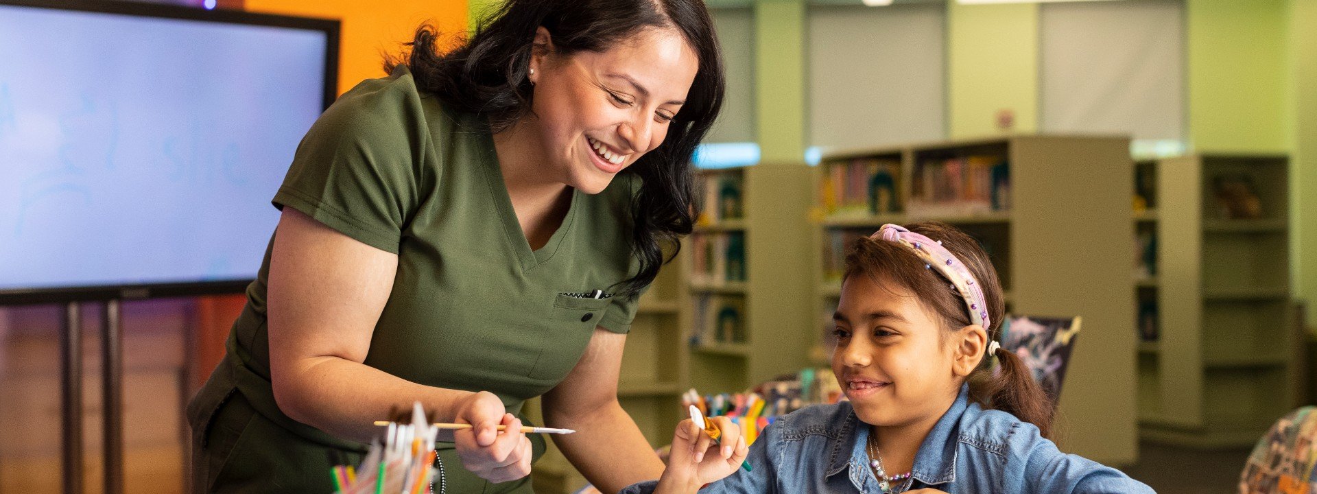 woman helping a little girl with arts and crafts