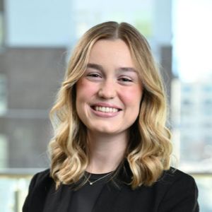 Professional headshot of a smiling woman with blonde hair in a black top