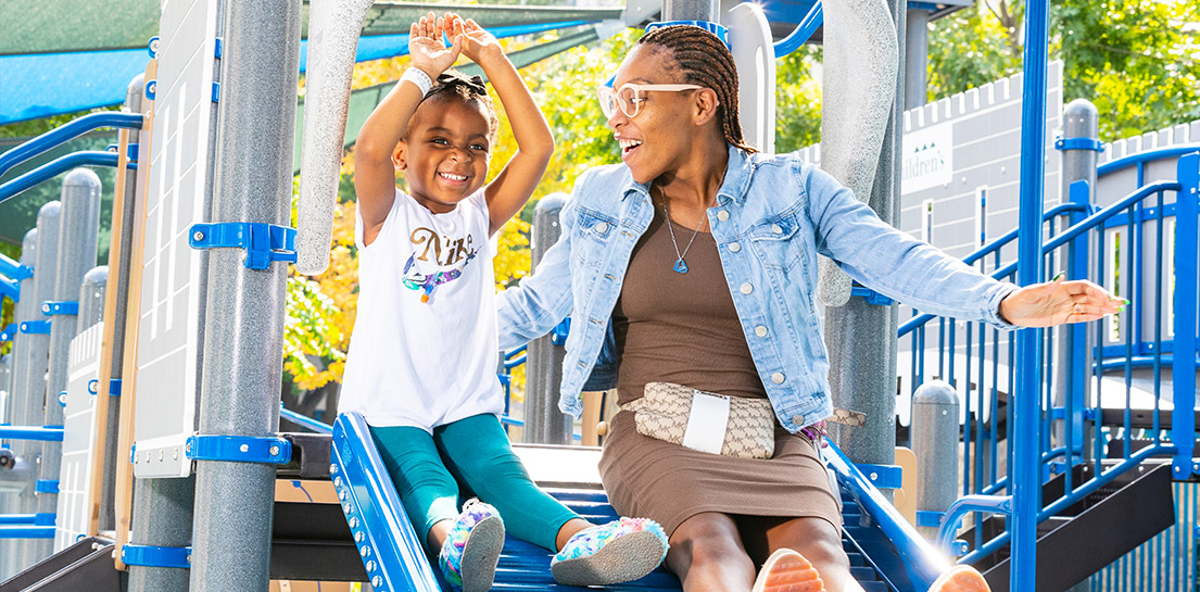 Happy mom and child on a blue playground slide. Children's sign on a castle wall
