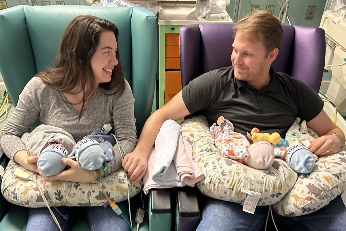 Mom and dad with quadruplets in Cook Children&rsquo;s NICU, each holding 2 babies - 3 boys and 1 girl