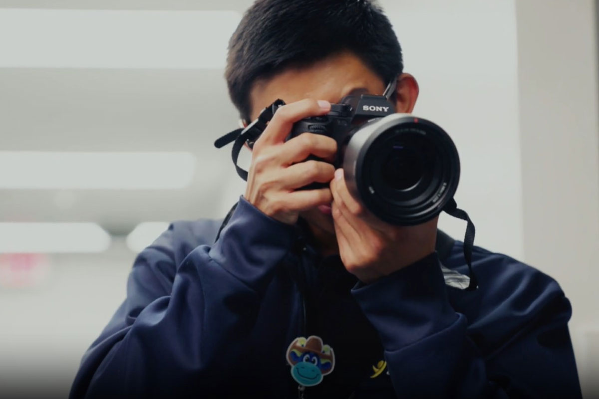 Jane Justin school graduate Eduardo holding camera and taking photos in his new career at Cook Children's