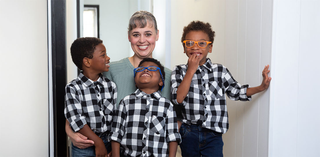 Rebekah Jones, RN standing in a hallway with her three sons in matching black and white checkered shirts
