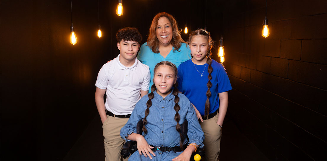 Dr. Liz Piñon with her triplets standing under twinkling lights