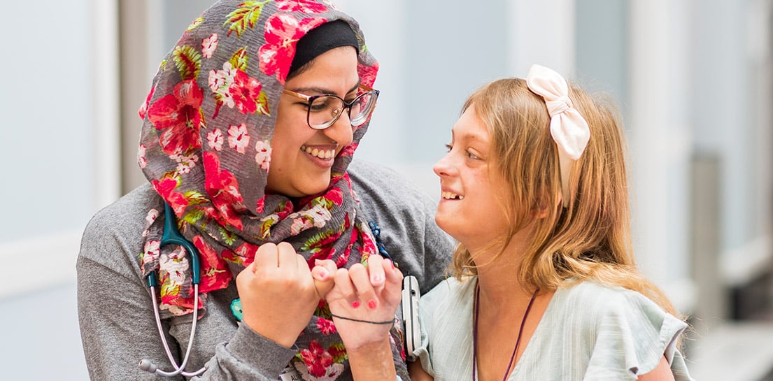 Doctor wearing floral head scarf making a pinky promise with blonde patient