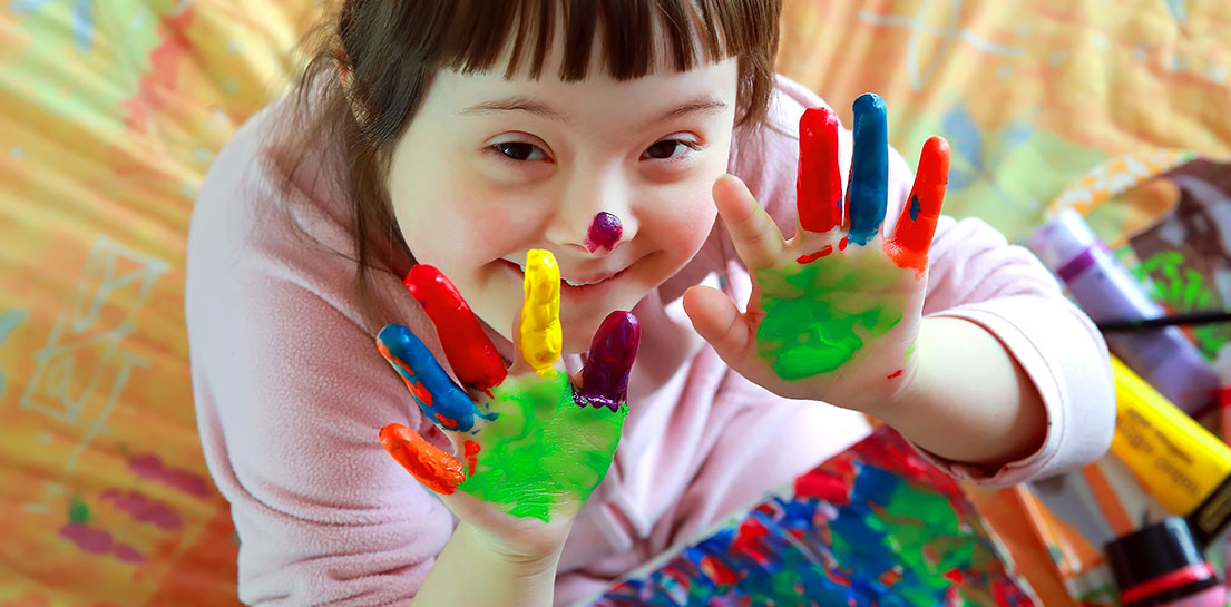 Young smiling girl with fingers covered in paint