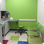 Bright green waiting room with counter, green stool, three chairs, colorful floor