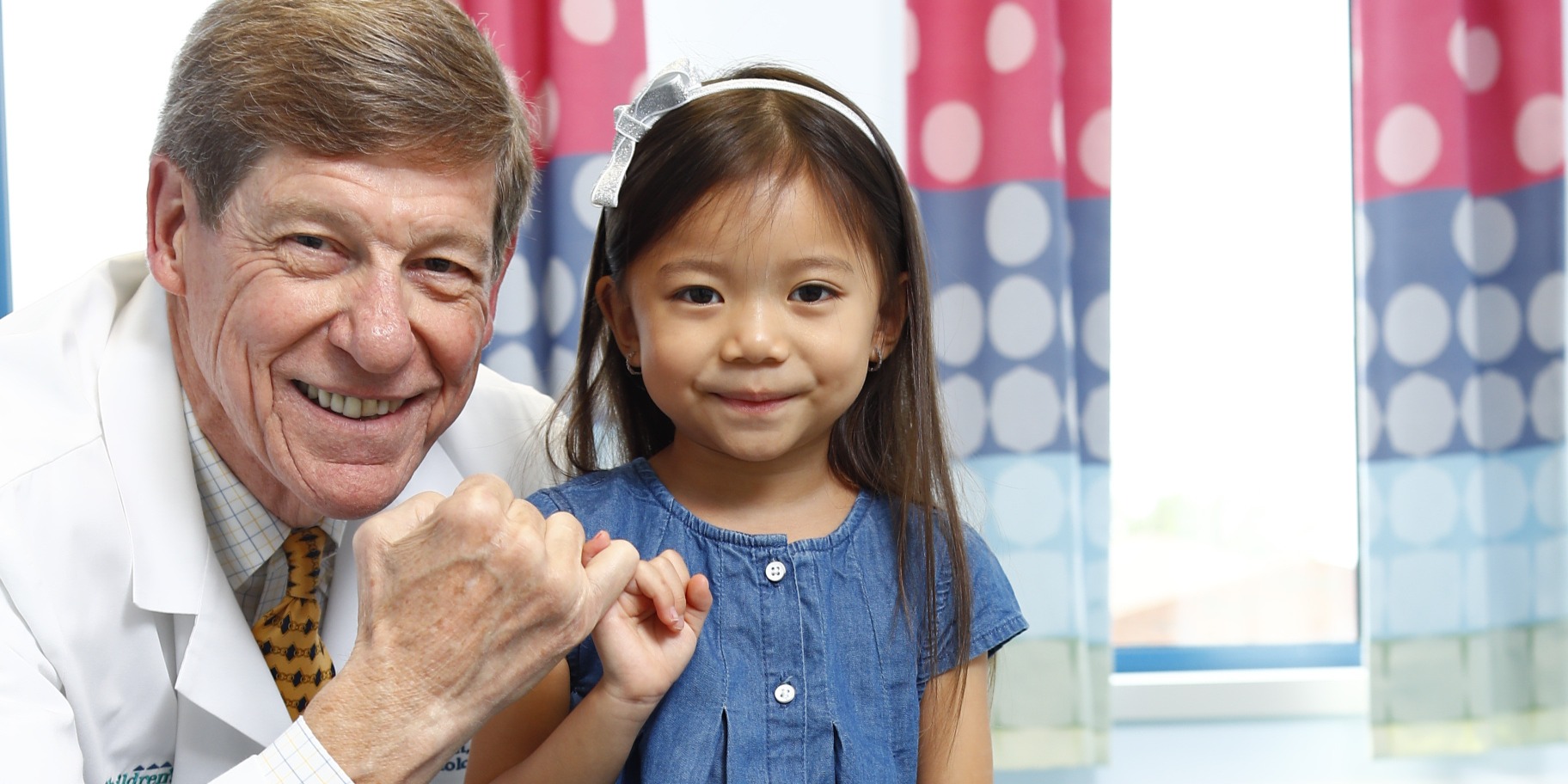 Endowed Chair and endocrinologist, Don Wilson, M.D., smiles with his patient as they hold their hands up making a pinky promise gesture