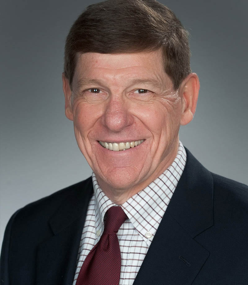 Smiling man in dark suit, checked shirt, and red tie