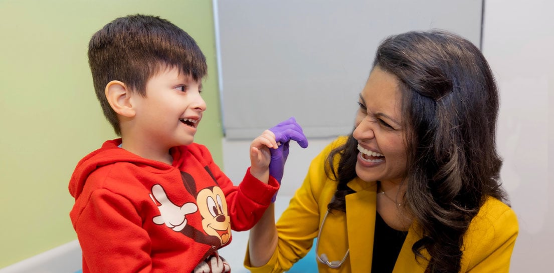 Endowed Chair Sani Roy, M.D., smiles and locks pinkies with a young male patient