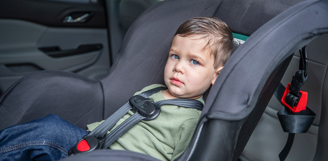 Boy in car seat with damp hair from sweating