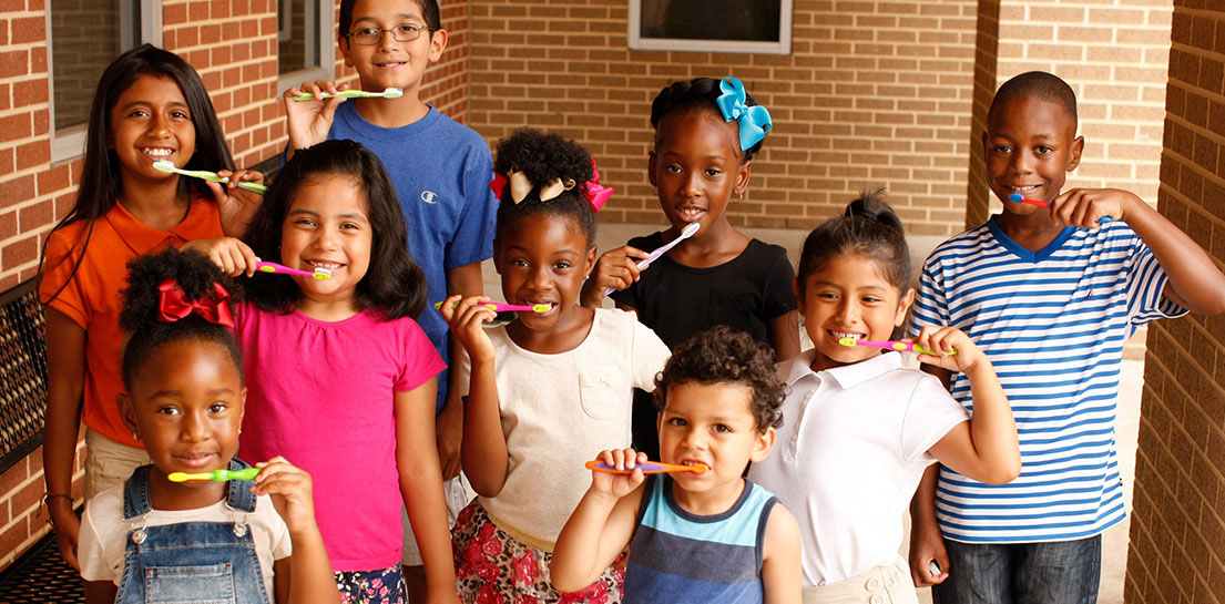 Large group of young children holding up their toothbrushes