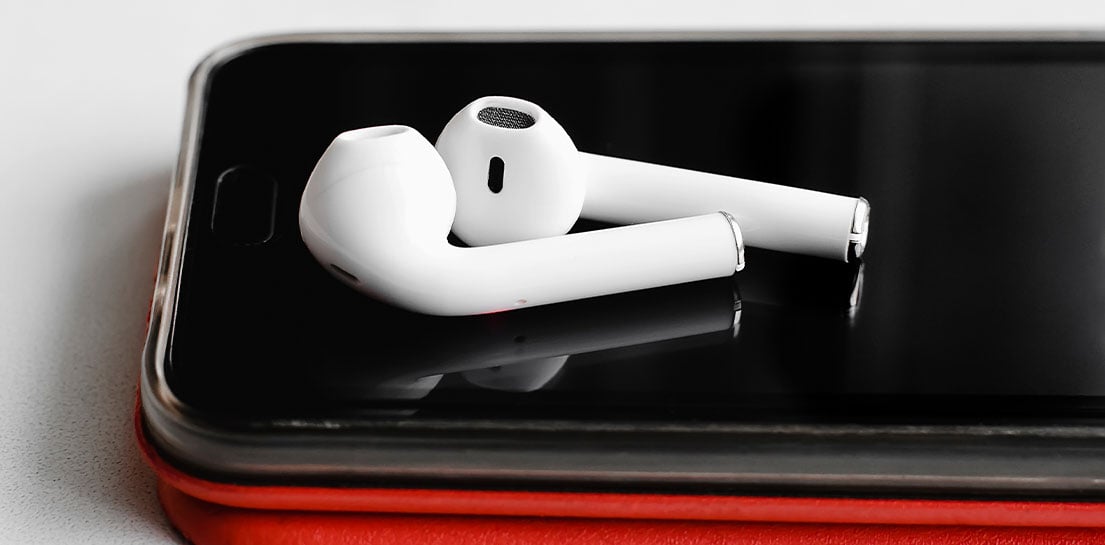 White earbuds laying on top of an iPhone
