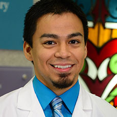 Smiling man with a goatee in a white lab coat and blue shirt and tie