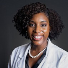 Smiling Black woman in a white lab coat and pearl necklace, with dark curly hair