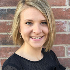 Professional headshot of a smiling woman with blonde hair and a dark top