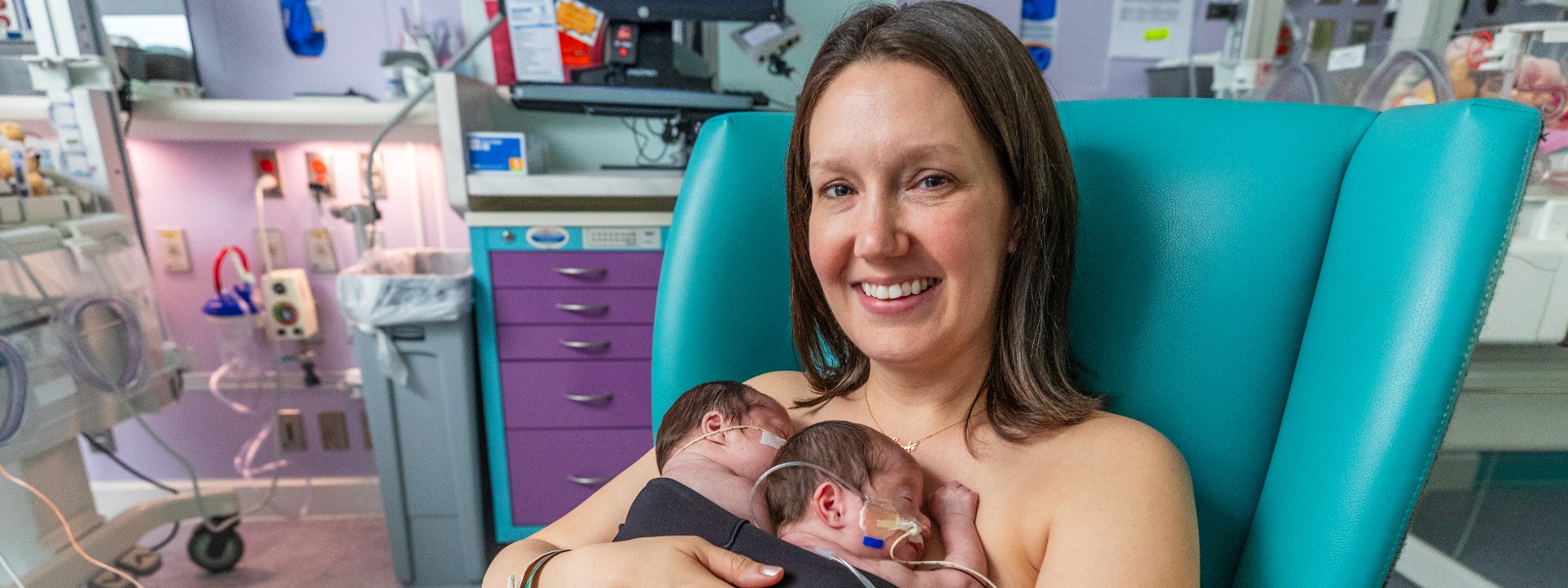 mother holding twin babies in kangaroo hold