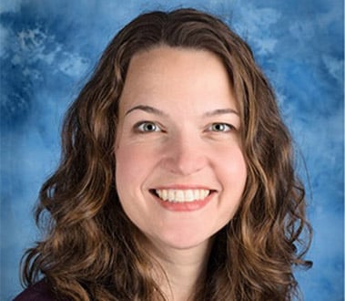 Smiling woman with long brown hair smiles against a mottled blue background