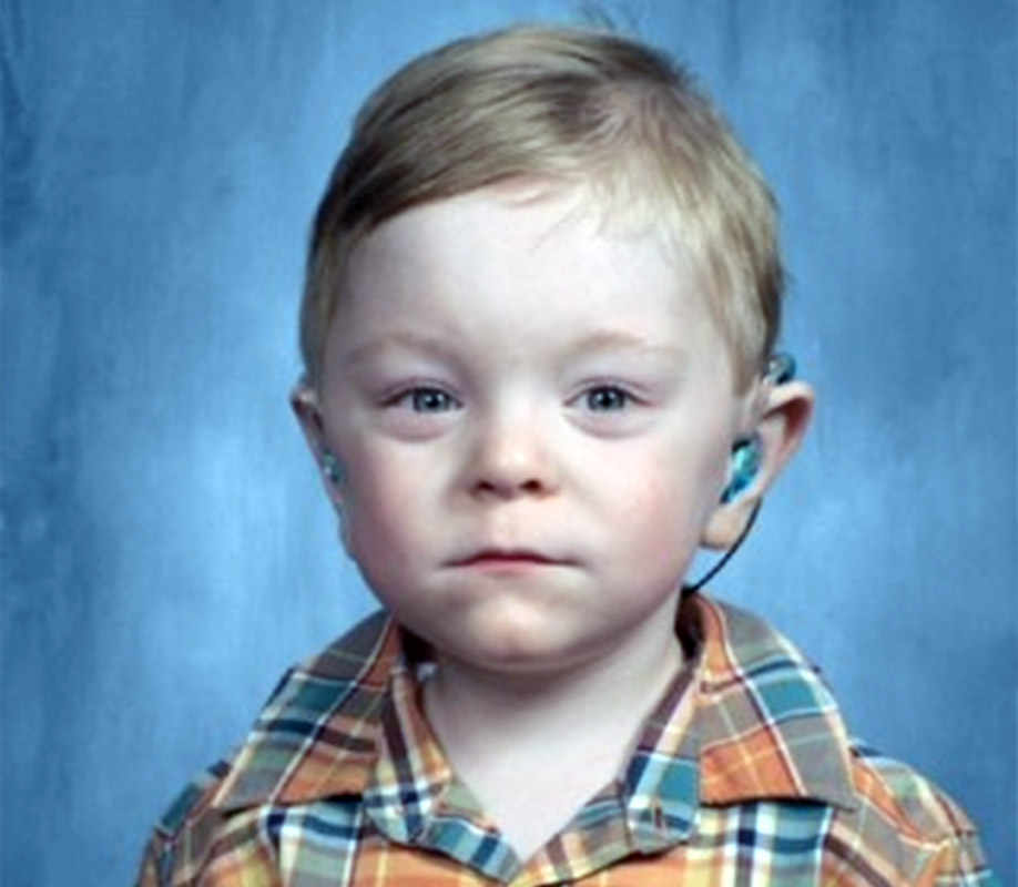Young child with blonde hair wearing blue hearing aids in both ears